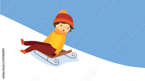 The boy goes down the hill on a sled sitting sideways