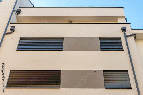 drainpipes on the wall of a modern residential multi-storey building, the windows are covered with wooden shutters