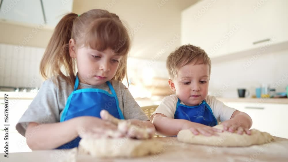 children making dough in the kitchen. baby boy cook in the kitchen knead dough and flour indoors. happy lifestyle family kid dream concept. children play cooking dough together at home children making dough in the kitchen. baby boy cook in the kitchen knead dough and flour indoors. happy lifestyle family kid dream concept. children play cooking dough together at home