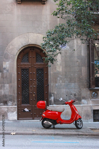 A red scooter is parked on the street in Europe  Spain  autumn