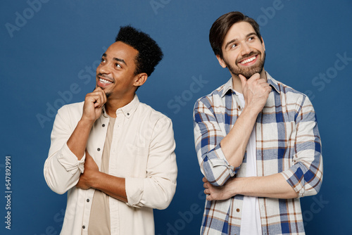 Young two friends minded pensive men 20s wear white casual shirts looking aside on dreamful area prop up chin together think isolated plain dark royal navy blue background. People lifestyle concept.