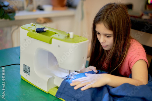 A young girl sews on a sewing machine at home.Lifestyle. Hobbies and hobbies, creativity, teaching children.