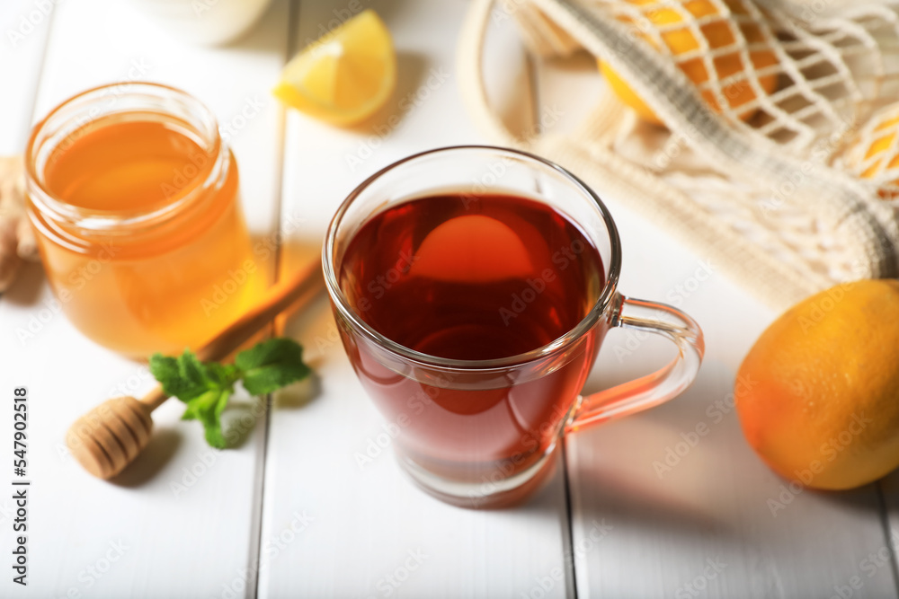 Cup of delicious ginger tea and ingredients on white wooden table, closeup Cup of delicious ginger tea and ingredients on white wooden table, closeup