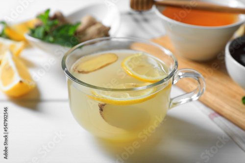 Delicious ginger tea and ingredients on white wooden table