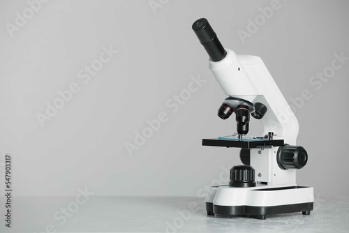 Modern microscope on grey background. Space for text