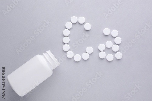 Open bottle and calcium symbol made of white pills on light grey background, flat lay