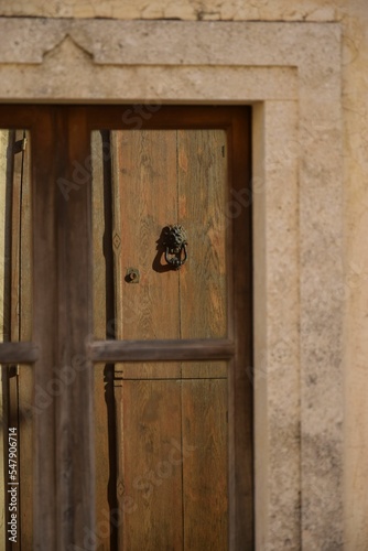 Vertical shot of an antique Sardinian wooden door with rusty decorative iron and knocker photo