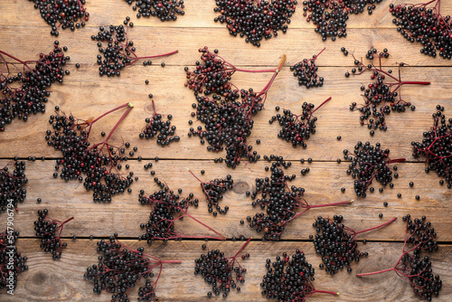 Many elderberries (Sambucus) on wooden background, flat lay