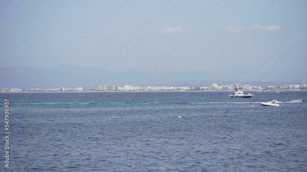 Two seagulls flying over the mediterranean sea with two boats in the background Two seagulls flying over the mediterranean sea with two boats in the background