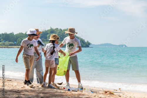 Children with family eco volunteer wearing in summer cloth clean collecting on beach from garbage, plastic, hold trash green bags on beach care of environment is save earth day concept.