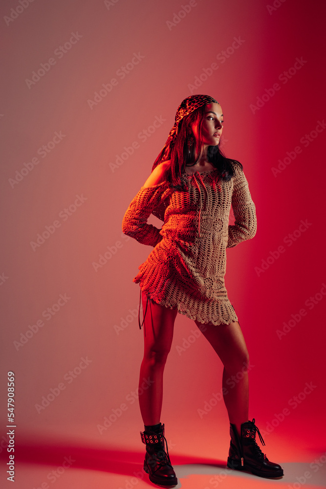 Young woman poses against red background with red backlight. Young woman poses against red background with red backlight.