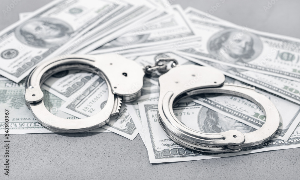 Handcuffs on US dollar banknotes money background. Corruption or financial crime concept Handcuffs on US dollar banknotes money background. Corruption or financial crime concept