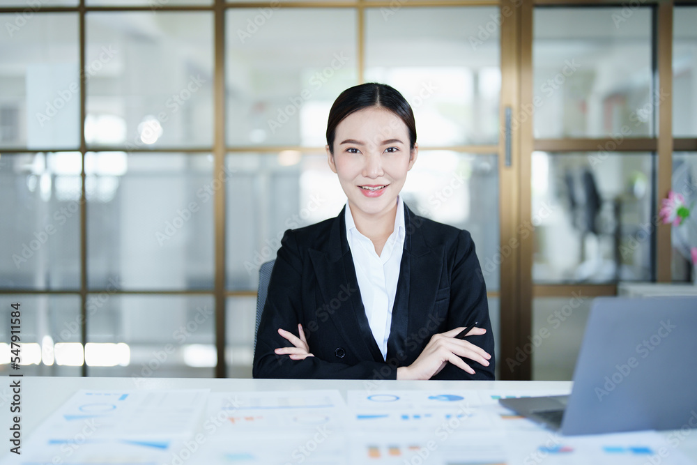 Portrait of a thoughtful Asian businesswoman looking at financial statements and making marketing plans using a computer on her desk Portrait of a thoughtful Asian businesswoman looking at financial statements and making marketing plans using a computer on her desk