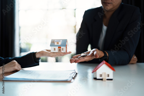 Accountant, businessman, real estate agent, Asian business woman handing keys to customers along with house after customers to sign