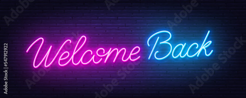 Welcome Back neon quote on brick wall background. photo