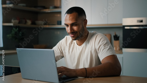 Foto Smiling African millennial man guy American male user freelancer at home kitchen