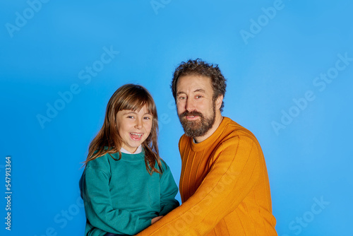 Family portrait father and 6 year old daughter. showing happiness on isolated blue studio background. Father day parenthood childhood concept © JORGE CORCUERA