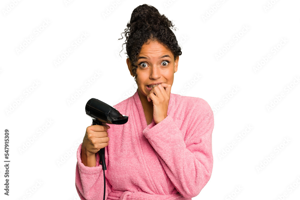Young brazilian woman wearing a pink bathrobe holding an hairdryer isolated biting fingernails, nervous and very anxious. - obrazy, fototapety, plakaty 