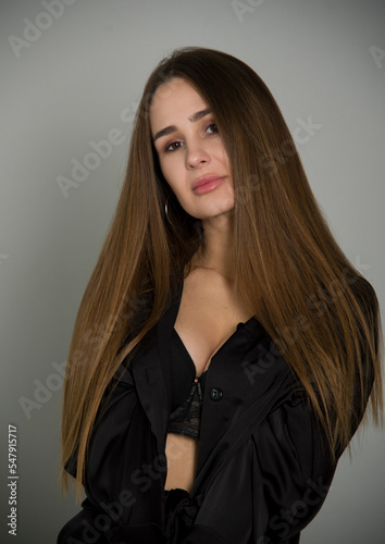 sensual portrait of beautiful young brunette woman with long hair on grey background