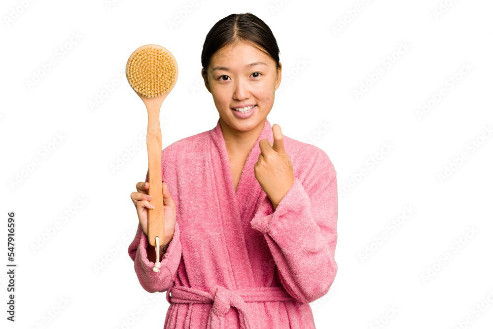 Young asian woman holding a shower brush isolated pointing with finger at you as if inviting come closer. Young asian woman holding a shower brush isolated pointing with finger at you as if inviting come closer.
