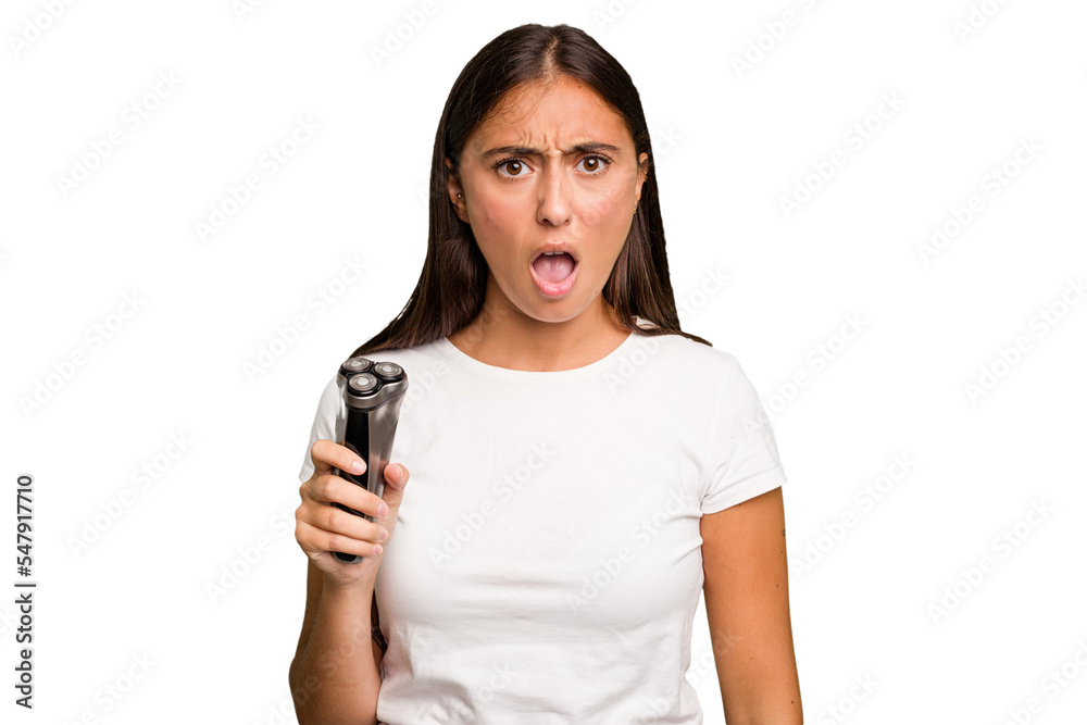 Young caucasian woman holding a razor isolated screaming very angry and aggressive.