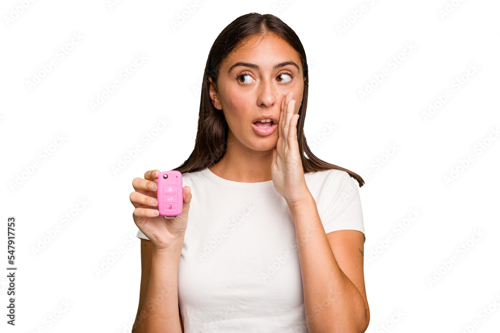 Young caucasian woman holding a car keys isolated is saying a secret hot braking news and looking aside Young caucasian woman holding a car keys isolated is saying a secret hot braking news and looking aside