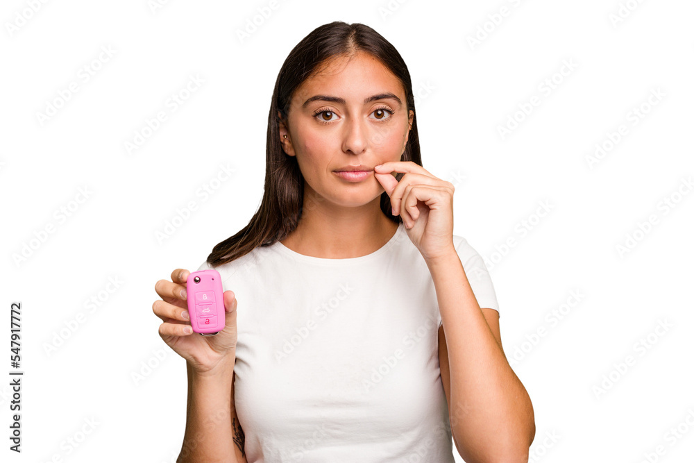 Young caucasian woman holding a car keys isolated with fingers on lips keeping a secret. Young caucasian woman holding a car keys isolated with fingers on lips keeping a secret.