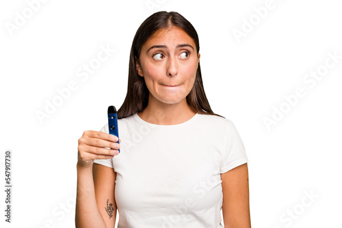 Young caucasian woman holding a electronic cigarette confused, feels doubtful and unsure.