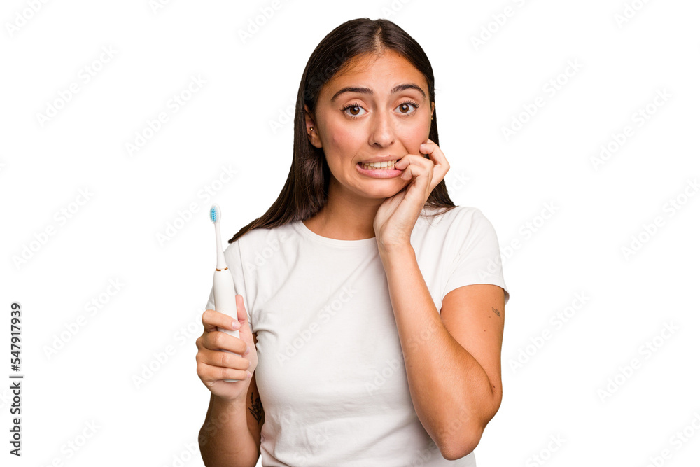Young caucasian woman holding an electric toothbrush isolated biting fingernails, nervous and very anxious. Young caucasian woman holding an electric toothbrush isolated biting fingernails, nervous and very anxious.