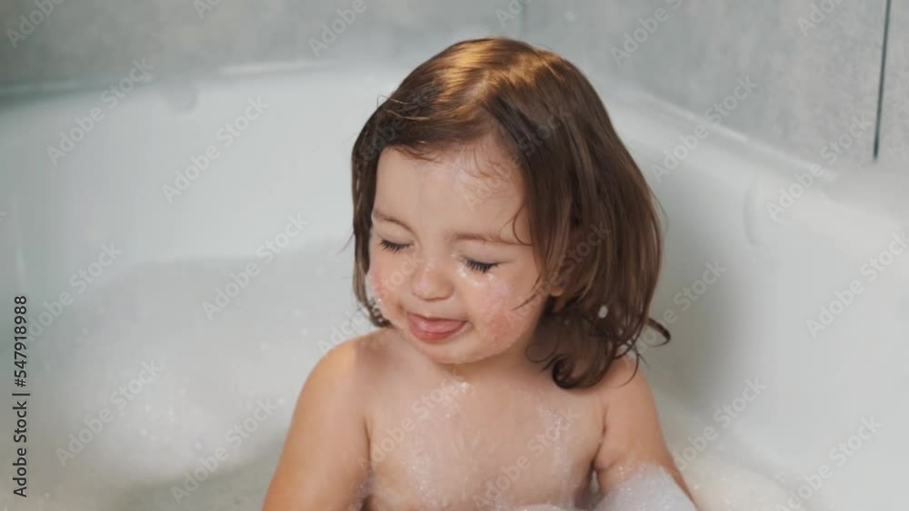 close-up portrait A little two-year-old child girl plays with foam in the bathroom close-up portrait A little two-year-old child girl plays with foam in the bathroom