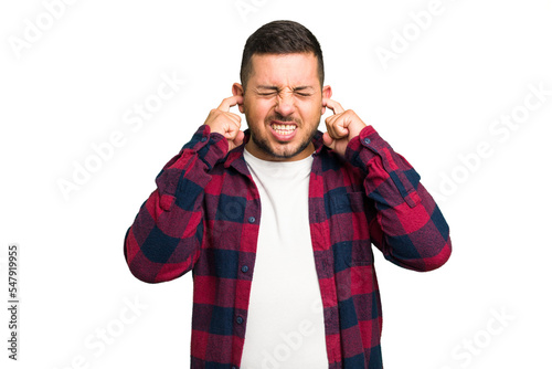 Young caucasian man isolated covering ears with fingers, stressed and desperate by a loudly ambient.