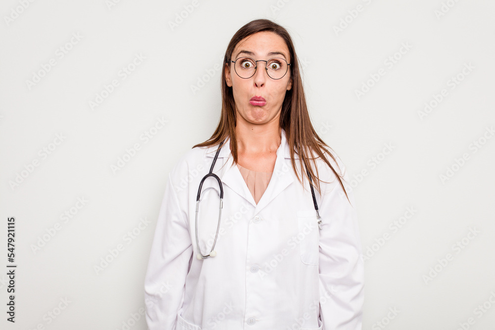 Young doctor woman isolated on white background shrugs shoulders and open eyes confused. Young doctor woman isolated on white background shrugs shoulders and open eyes confused.