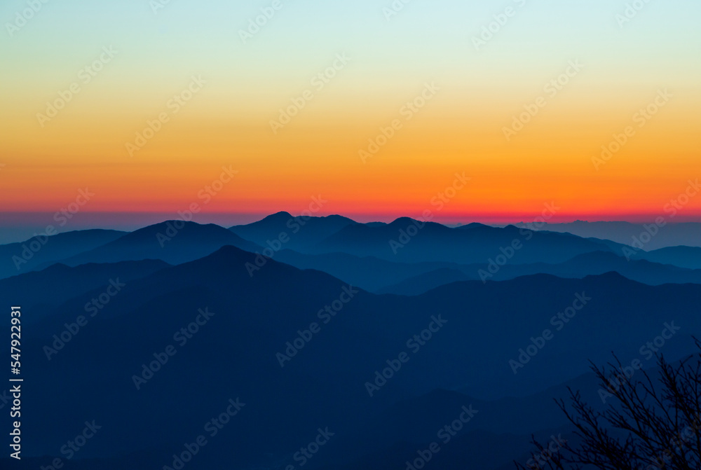 夜明けの三つ峠山頂から日の出前のオレンジ色に染まる丹沢山塊