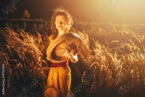 Fotobehang beautiful shamanic girl playing on shaman frame drum in the nature