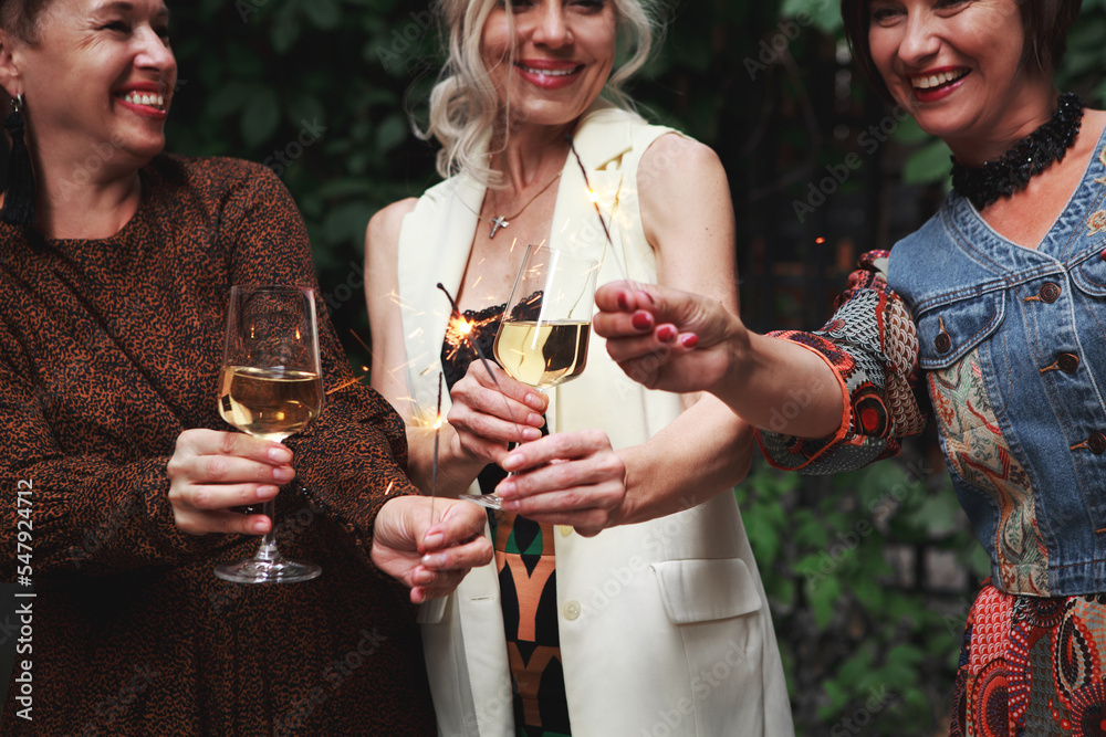 Φωτογραφία Happy Mature women Friends celebrate new year and laughing, hold sparklers and g