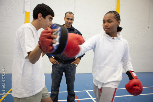 Sports Students: Kickboxing. Teenage boys learning martial arts skills under the supervision of her teacher. From a series of related images. photo