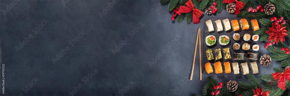 Sushi set for Christmas New Year party, winter holiday food delivery menu mockup. Sushi set on slate board, with Xmas decoration copy space - obrazy, fototapety, plakaty 