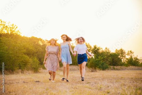 A group of girlfriends jumps and runs outdoors. A group of female friends hugs and enjoys the sunset in nature. Laughter, smiles and joy.