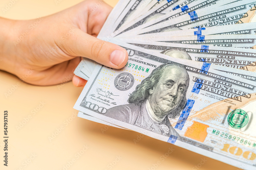 Men's hand holds a fan of dollars on pastel background. Finance concept. Men's hand holds a fan of dollars on pastel background. Finance concept.