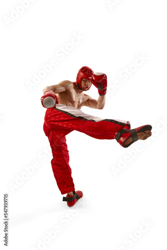 Young professional kickboxer wearing helmet and boxing gloves in motion isolated on white background. Sport, competition, energy, combat sports