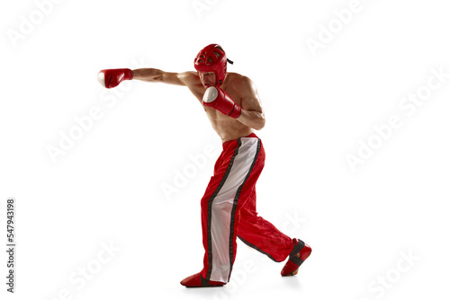 Punch. Young muscled athlete, professional kickboxer in protective helmet and boxing gloves in action isolated on white background. Sport, competition, energy, combat sports