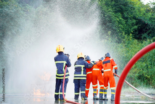 Firefighter spraying water to fire for heat protection, Team fireman training fighting fire. photo