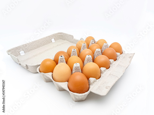 Cardboard egg box with fifteen brown eggs isolated on white background. photo