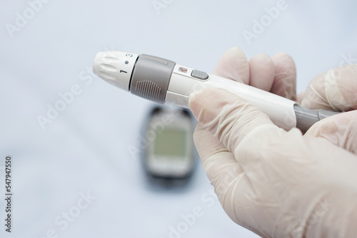 Closeup of doctor hands wear gloves holding syringe for insulin to check blood sugar level by glucose and a blood reader is blur on the back.