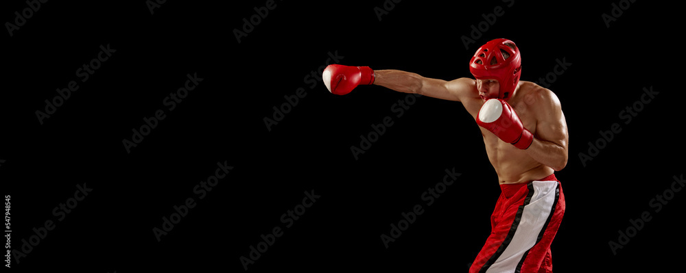 Studio shot of male kickboxer, mma fighter in motion and action isolated over dark background. Muay thai. Sport, competition, energy, combat sports. Red and black Studio shot of male kickboxer, mma fighter in motion and action isolated over dark background. Muay thai. Sport, competition, energy, combat sports. Red and black