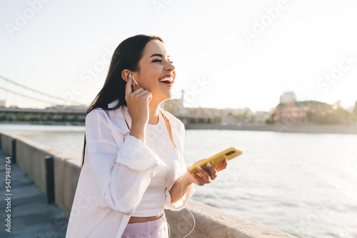 Tablou canvas Female in earphones having fun on embankment