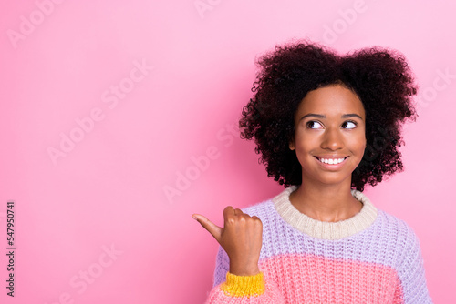 Portrait of good mood girl with wavy hairstyle dressed knit sweatshirt directing look empty space isolated on pink color background