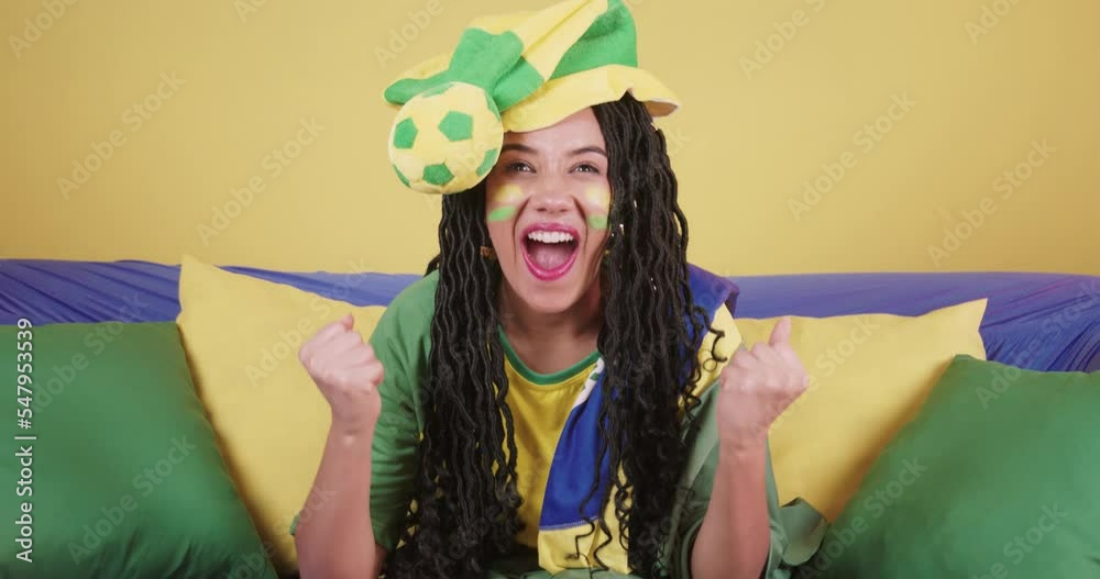 black woman soccer fan from Brazil, cheering on the sofa