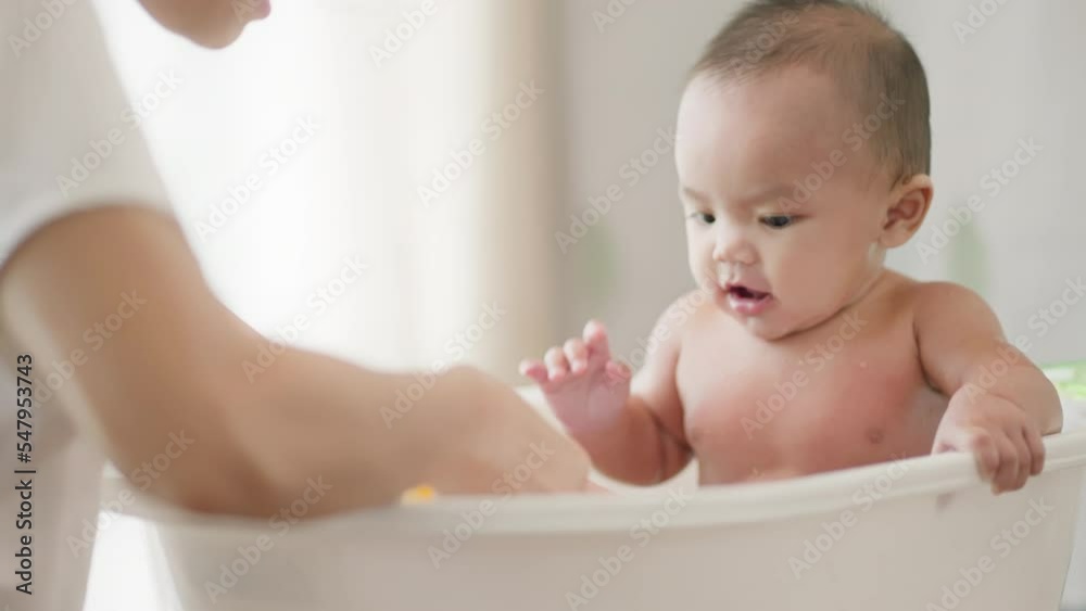 young Asian mother is Bathing with her newborn baby In Bathtub at home in morning.Concept of mom and newborn,baby,parenthood,motherhood,childhood,New life,maternity,love,new family member.
