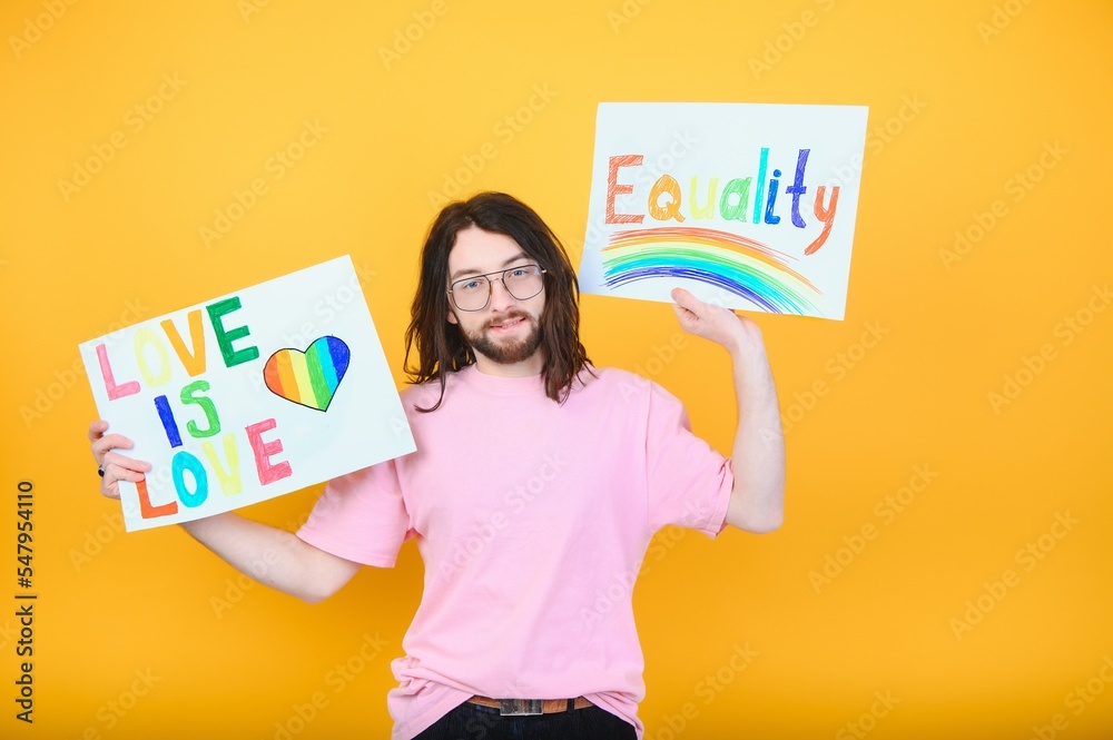 Attractive gay caucasian man holding a protest sign during a LGBT pride parade. Equality. Attractive gay caucasian man holding a protest sign during a LGBT pride parade. Equality.